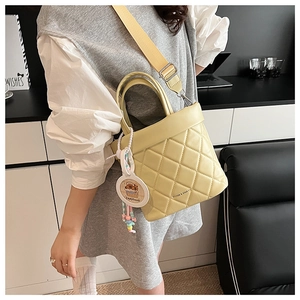 Detail of yellow quilted PU leather bag with Capybara charm and wide woven strap