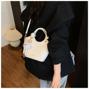 Détails d'un sac seau blanc en cuir gaufré avec charme peluche et texte doré