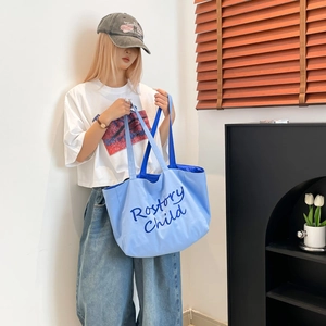 Grand sac cabas bleu en toile avec inscription montré dans un décor élégant