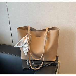 Detail of khaki lychee leather tote bag with elegant silk scarf and branding logo