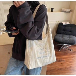 Dettaglio della borsa tote crema con ricamo blu e una trama plissettata molto elegante