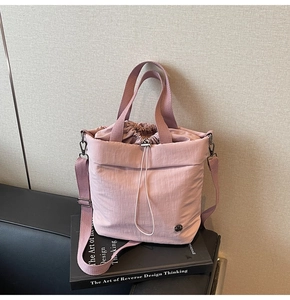 Detailed view of dusty pink bucket bag with drawstring closure and metal logo on art books
