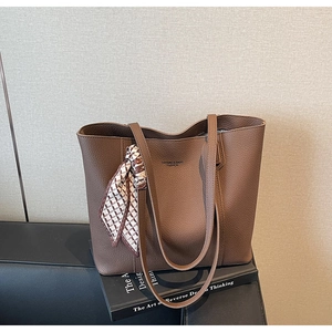 Detail of dark brown lychee grain leather tote bag with geometric silk scarf and logo