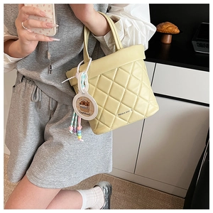 Detail of yellow quilted tote bag with cute capybara pendant and colorful bead chain