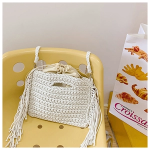 Detailed close-up of white crochet tote bag featuring long fringes and drawstring lining