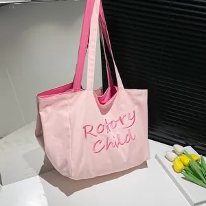 Détail du cabas en toile rose avec broderie fuchsia éclatante et double bandoulière