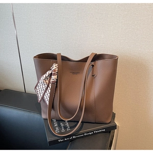 Detail of a brown lychee pattern leather tote bag with checkerboard silk scarf accessory