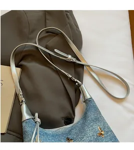 Detailansicht der Denim-Umhängetasche mit silbernem Schmetterling und Trageriemen