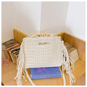 Detail of bohemian cotton crochet tote bag with woven tassels and drawstring lining