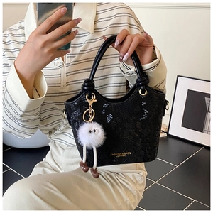 Détail du sac seau noir motif python avec breloque en peluche et logo doré
