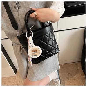 Detail of black quilted crossbody bag with cute white Capybara cartoon pendant