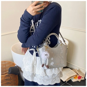 Détail du sac à main argenté texture serpent avec charm monstre en peluche blanc et bandoulière