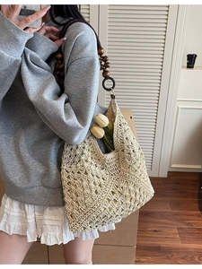 Woven straw tote bag with dark brown wood bead handle for beach or casual outings