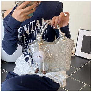 Détail du sac seau argenté à motif python avec breloque peluche et boucles dorées