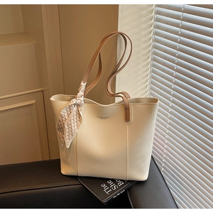 Detail of cream-colored lychee leather tote bag with a decorative silk scarf on handle