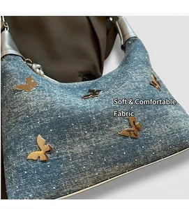Makro-Detail der Denim-Umhängetasche mit goldenen Schmetterlingsnieten und Strasssteinen