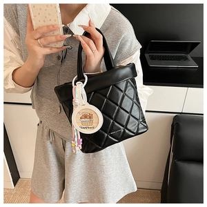 Close-up of quilted black bucket bag featuring a cute Capybara charm with colorful beads