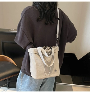 Detail of off-white drawstring bucket tote bag with adjustable strap and metallic logo