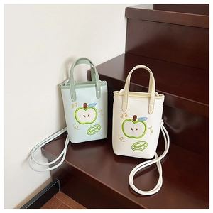 Detail of apple embroidery and music symbols on mini crossbody bags in green and cream