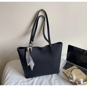 Black pebbled leather tote bag with decorative silk scarf and laptop in a home office setting