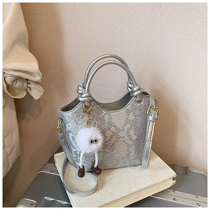 Détail du sac seau argenté à motif serpent avec poignée nouée et breloque peluche