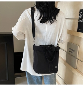 Back view of a model wearing a versatile black canvas bucket bag with adjustable strap
