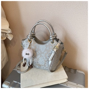 Détail du sac seau argenté texture serpent avec breloque peluche et bandoulière réglable