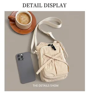 Detailed close-up of cream nylon crossbody bag with bow texture and wide strap