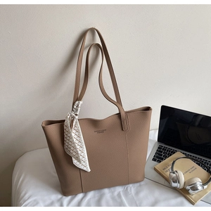 Brown leather tote bag featuring a decorative silk scarf on the handle with a laptop