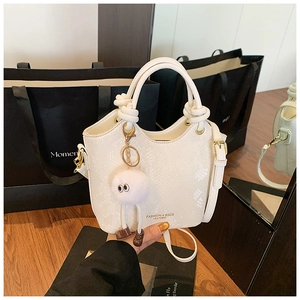 Détail du sac seau blanc à texture serpent avec breloque peluche monstre et poignée