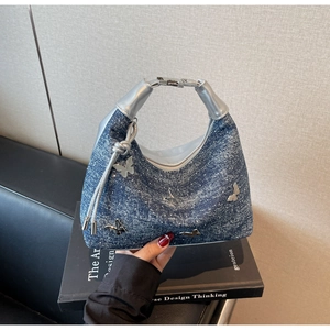 Détail du sac hobo en jean bleu avec papillons argentés et poignée métallique
