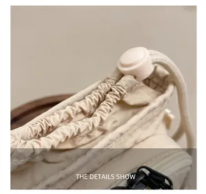 Detail showing the adjustable drawstring closure and cord lock on a beige nylon crossbody bag
