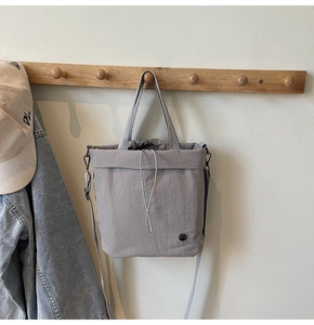 Detail of grey drawstring tote bag with nylon texture hanging in a casual lifestyle setting