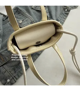 Detail view of the magnetic closure on the off-white leather bucket bag with inner lining