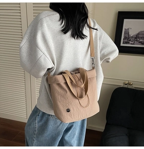 Detail of khaki drawstring bucket bag with adjustable shoulder strap and round brand logo
