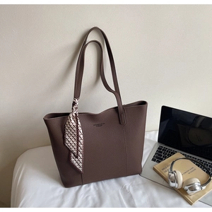 Close-up of brown lychee leather tote bag with geometric scarf and laptop context