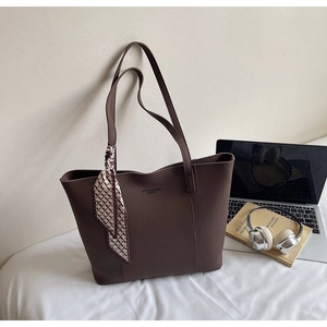 Detail of dark brown tote bag with textured finish and a decorative silk scarf on the handle