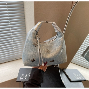 Détail du sac papillon en denim bleu clair avec strass brillants et poignée métal