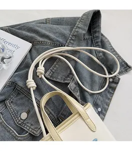 Close-up of cream-white apple handbag featuring knot strap and precise stitching details
