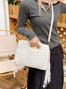 White cotton crochet tote bag with long tassels and drawstring interior in outdoor setting