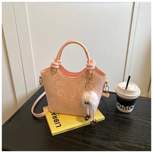 Détail d'un sac seau rose à motif serpent avec un pendentif peluche mignon et créatif