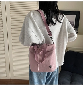 Detail of light pink nylon bucket bag with drawstring closure and adjustable strap