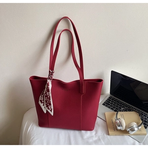 Close-up of deep red tote bag with lychee texture and heart pattern decorative scarf