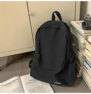 Detailed view of a black minimalist school backpack with a side pocket and brand label