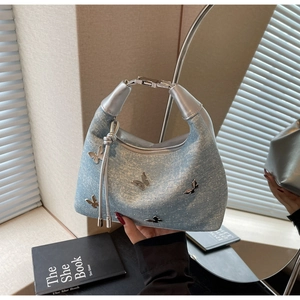 Détail du sac à main en denim bleu clair avec papillon en métal argenté et strass