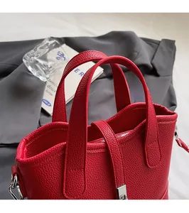 Dettaglio borsa rossa in pelle con grana litchi, fibbia in metallo e doppi manici
