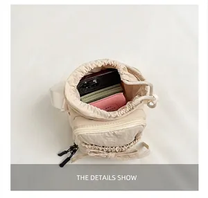 Detail showing capacity of cream nylon drawstring crossbody bag with phone and cards