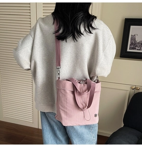 Detail of pink canvas drawstring bucket bag worn by model showing texture and logo