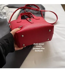 Dettaglio del fondo della borsa in pelle rossa con piedini protettivi e grana martellata