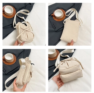 Detail view of beige nylon crossbody bag featuring multi-pocket zippers and bow detail
